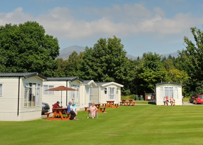 People sitting on a bench outside of a static caravan in Fonab caravan park