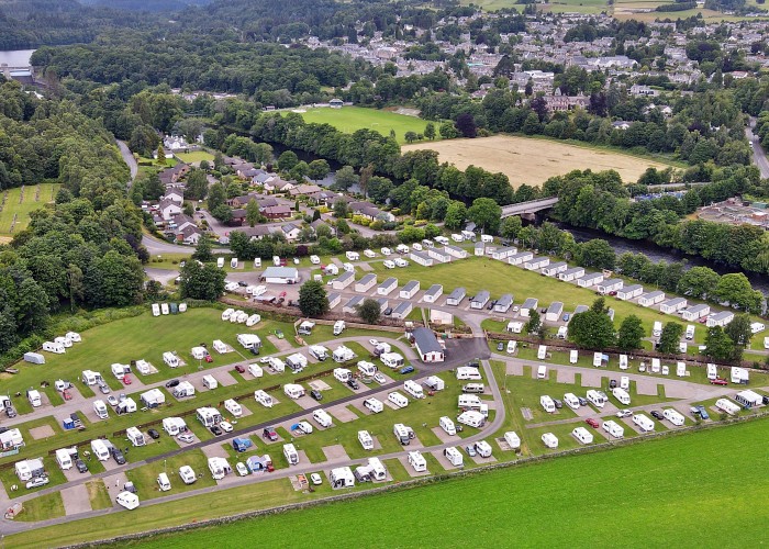 Ariel view of the back side of Fonab Caravan Park, Multiple rows of tourer's and campervans along with rows of static holiday homes in the second triangle field of Fonab. A view of the town of Pitlochry can be seen in the far away background