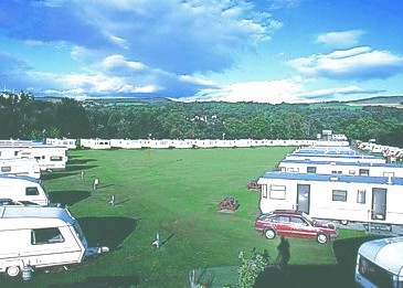 An old photograph of Fonab Caravan Park from the 80's or 90's with 80 styled caravans and static homes displayed around the edge of Fonabs Triangle green grass area.