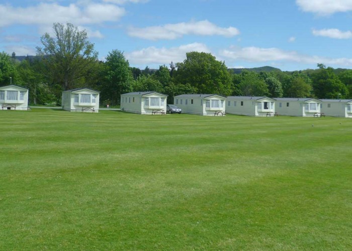 A landscape image of rows of the static caravans on offer at fonab caravan park. Over 8 static homes that are leading onto a larger open grassed area for guests to use.