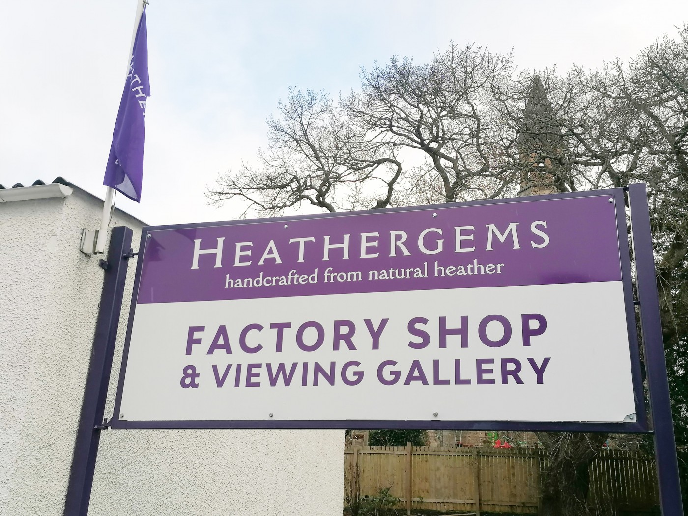 Outside signage of Heathergems with branded purple flag